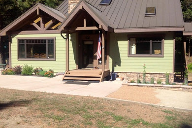 Example of a mid-sized mountain style green one-story wood exterior home design in Other with a metal roof