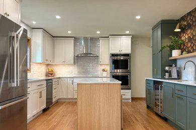 Example of a mid-sized transitional l-shaped medium tone wood floor and brown floor eat-in kitchen design in Other with an undermount sink, flat-panel cabinets, white cabinets, quartz countertops, gray backsplash, ceramic backsplash, stainless steel appliances, an island and white countertops
