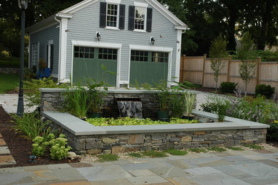 This is an example of a mid-sized traditional backyard partial sun formal garden in Providence with with pond and natural stone pavers.