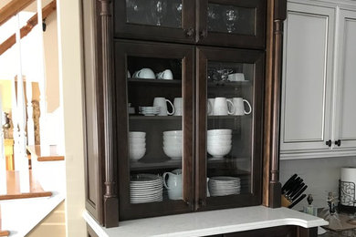 Large elegant medium tone wood floor and brown floor eat-in kitchen photo in New York with a farmhouse sink, recessed-panel cabinets, dark wood cabinets, quartz countertops, white backsplash, ceramic backsplash, stainless steel appliances and no island