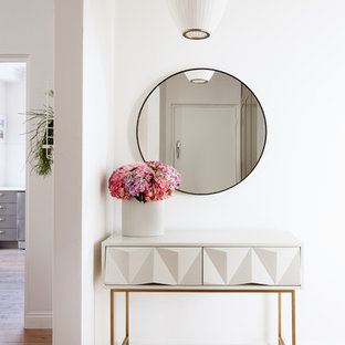 Ejemplo de hall ecléctico, pequeño, con paredes blancas, suelo de madera clara, puerta simple, puerta blanca y suelo blanco