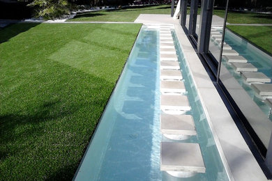 Diseño de acceso privado moderno en primavera en patio delantero con estanque, exposición parcial al sol y adoquines de piedra natural