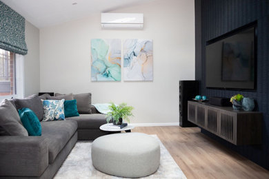 Photo of a mid-sized contemporary living room in Sydney with multi-coloured walls, laminate floors, a built-in media wall and beige floor.