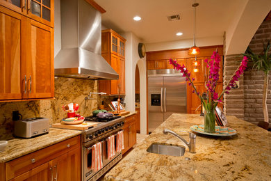 Danish travertine floor open concept kitchen photo in Phoenix with shaker cabinets, medium tone wood cabinets, granite countertops, multicolored backsplash, stone slab backsplash, stainless steel appliances, an island and a drop-in sink