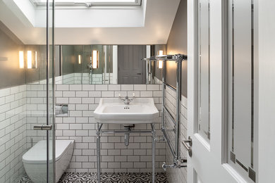 This is an example of a small traditional bathroom in London with a wall-mount toilet, white tile, grey walls, ceramic floors, multi-coloured floor, a console sink and subway tile.