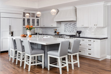 Example of a mid-sized transitional l-shaped dark wood floor and brown floor open concept kitchen design in San Francisco with white cabinets, quartz countertops, white backsplash, stainless steel appliances, an island, an undermount sink, shaker cabinets and subway tile backsplash