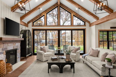 Large beach style open concept medium tone wood floor, brown floor and vaulted ceiling family room photo in Minneapolis with a standard fireplace, a stone fireplace and a wall-mounted tv