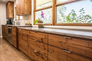 Inspiration for a small modern galley medium tone wood floor and brown floor eat-in kitchen remodel in Wichita with a drop-in sink, flat-panel cabinets, brown cabinets, quartzite countertops, white backsplash, glass tile backsplash, stainless steel appliances and a peninsula