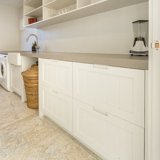ネイピアの小さいシャビーシック調のおしゃれな家事室 (エプロンフロントシンク、落し込みパネル扉のキャビネット、白いキャビネット、クオーツストーンカウンター、白い壁、セラミックタイルの床、左右配置の洗濯機・乾燥機、マルチカラーの床、グレーのキッチンカウンター) の写真