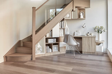 Design ideas for a small contemporary study in Surrey with white walls, medium hardwood flooring, a built-in desk and brown floors.
