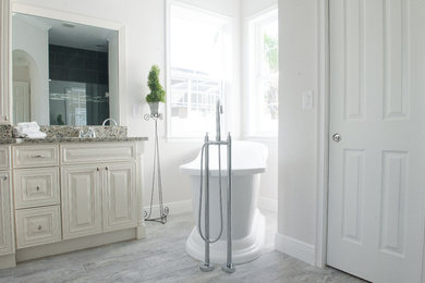 Bathroom - farmhouse master gray tile and porcelain tile porcelain tile bathroom idea in Orlando with raised-panel cabinets, distressed cabinets, gray walls, an undermount sink and granite countertops