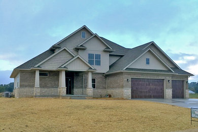 Beige two-story brick house exterior photo in Other with a shingle roof