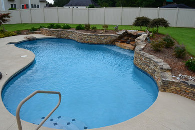 Design ideas for a mid-sized traditional backyard custom-shaped pool in Other with concrete slab.