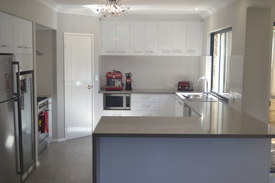 This is an example of a contemporary u-shaped kitchen in Perth with a double-bowl sink, flat-panel cabinets, white cabinets, stainless steel appliances and a peninsula.