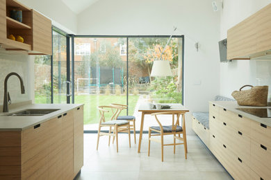 Große Moderne Wohnküche ohne Insel in U-Form mit flächenbündigen Schrankfronten, Quarzit-Arbeitsplatte, Glasrückwand und grauer Arbeitsplatte in Sussex