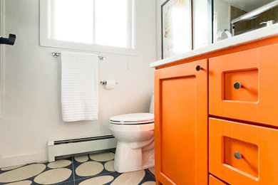Photo of a small modern bathroom in Burlington with recessed-panel cabinets, orange cabinets, an alcove tub, a shower/bathtub combo, a two-piece toilet, white walls, ceramic floors, an undermount sink, engineered quartz benchtops, blue floor, a sliding shower screen, white benchtops, a single vanity and a freestanding vanity.