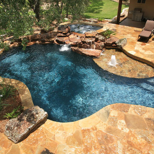 Mid-sized mountain style backyard stone and custom-shaped natural hot tub photo in Austin