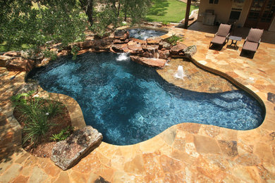 Mid-sized mountain style backyard stone and custom-shaped natural hot tub photo in Austin