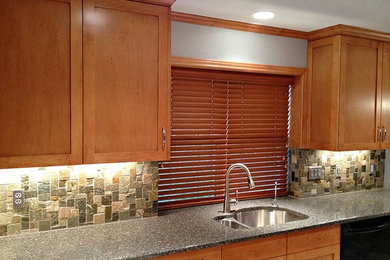 Kitchen - transitional kitchen idea in Austin with a double-bowl sink, medium tone wood cabinets, granite countertops, green backsplash, stone tile backsplash, stainless steel appliances and no island