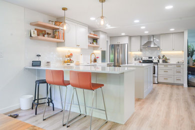 Eat-in kitchen - mid-sized contemporary u-shaped laminate floor and beige floor eat-in kitchen idea in Seattle with a farmhouse sink, shaker cabinets, white cabinets, quartzite countertops, white backsplash, ceramic backsplash, colored appliances, two islands and white countertops