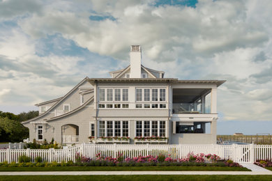 На фото: двухэтажный, серый частный загородный дом в морском стиле с двускатной крышей, крышей из гибкой черепицы, коричневой крышей и отделкой дранкой с