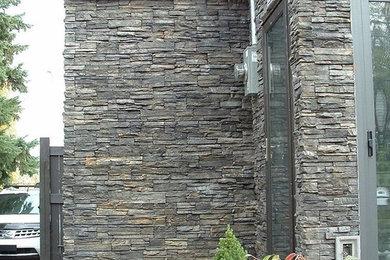 Example of a mid-sized transitional gray stone house exterior design in Other