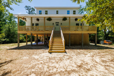 Example of a large beach style white two-story exterior home design in Other