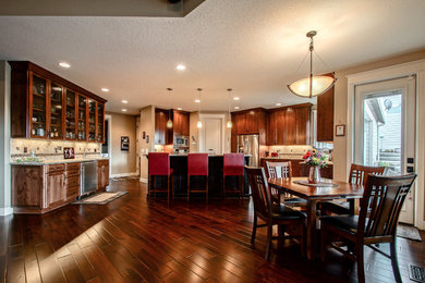 Example of an arts and crafts dark wood floor and brown floor kitchen design in Portland with an undermount sink, granite countertops, beige backsplash, porcelain backsplash and stainless steel appliances