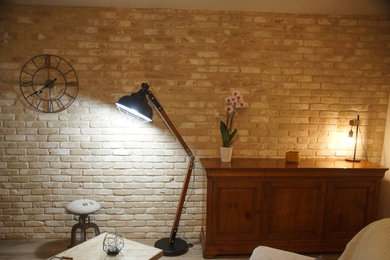 Cette image montre un salon urbain de taille moyenne et ouvert avec un mur beige, sol en stratifié, une cheminée d'angle, un manteau de cheminée en pierre, un téléviseur indépendant et un sol marron.