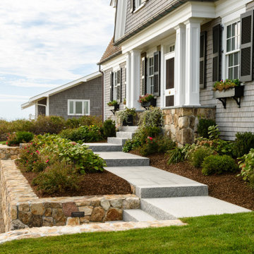 The front entrance hosts granite steps and vibrant lush greenery