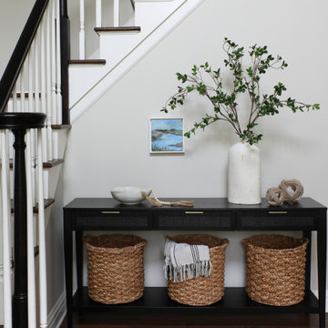 entry foyer with storage baskets and greenery and black stair railing