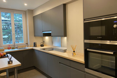 This is an example of a medium sized contemporary l-shaped open plan kitchen in Paris with flat-panel cabinets, grey cabinets, laminate countertops, metallic splashback and beige worktops.