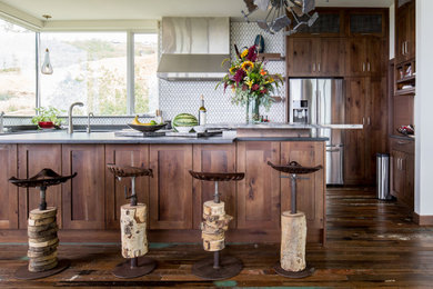 Photo of a rustic u-shaped kitchen in Los Angeles with a submerged sink, shaker cabinets, dark wood cabinets, white splashback, mosaic tiled splashback, stainless steel appliances, dark hardwood flooring, an island, brown floors and grey worktops.