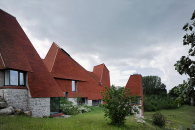 This is an example of an expansive and red contemporary clay detached house in Other with a tiled roof.