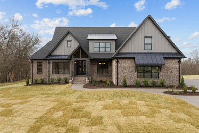 Example of a classic two-story board and batten house exterior design in Nashville with a shingle roof