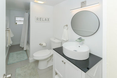 Inspiration for a mid-sized contemporary porcelain tile and beige floor bathroom remodel in Other with furniture-like cabinets, white cabinets, a two-piece toilet, white walls, a vessel sink, solid surface countertops and gray countertops