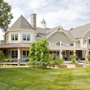 Klassisk inredning av ett mycket stort grått hus, med två våningar och vinylfasad