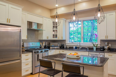 Mid-sized modern l-shaped kitchen in Boston with a single-bowl sink, recessed-panel cabinets, white cabinets, granite benchtops, grey splashback, matchstick tile splashback, stainless steel appliances, light hardwood floors, with island, beige floor and black benchtop.