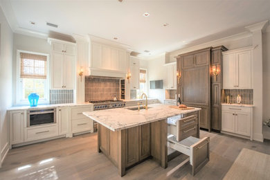 Inspiration for a large transitional l-shaped medium tone wood floor and gray floor eat-in kitchen remodel in Jacksonville with a single-bowl sink, recessed-panel cabinets, white cabinets, marble countertops, gray backsplash, ceramic backsplash, paneled appliances, an island and white countertops