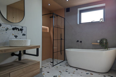 Photo of a large contemporary family bathroom in Other with flat-panel cabinets, light wood cabinets, a freestanding bath, a walk-in shower, a one-piece toilet, green walls, ceramic flooring, an integrated sink, wooden worktops, multi-coloured floors, an open shower, double sinks, a freestanding vanity unit and panelled walls.