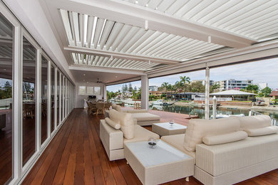 Large contemporary backyard deck in Brisbane with with dock and a roof extension.