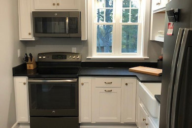 バーミングハムにある低価格の小さなトラディショナルスタイルのおしゃれなキッチン (エプロンフロントシンク、シェーカースタイル扉のキャビネット、白いキャビネット、ソープストーンカウンター、無垢フローリング、アイランドなし、茶色い床、黒いキッチンカウンター) の写真