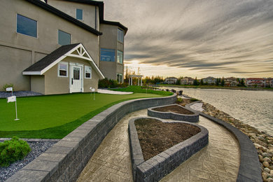 Inspiration for a large contemporary shade backyard stone retaining wall landscape in Calgary for summer.