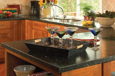 Example of a large kitchen pantry design in Cleveland with recessed-panel cabinets, medium tone wood cabinets, granite countertops and an island
