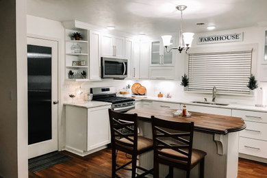 Example of a small farmhouse l-shaped vinyl floor and brown floor kitchen design in Other with an undermount sink, shaker cabinets, white cabinets, quartz countertops, stainless steel appliances and an island