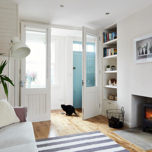 Foto di un piccolo soggiorno scandinavo aperto con pareti bianche, parquet chiaro, stufa a legna, cornice del camino in intonaco, nessuna TV e pavimento marrone