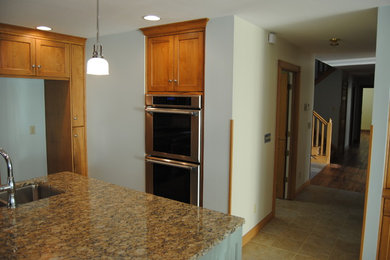 Eat-in kitchen - large traditional u-shaped ceramic tile eat-in kitchen idea in Other with a double-bowl sink, beaded inset cabinets, distressed cabinets, granite countertops, beige backsplash, stone tile backsplash, stainless steel appliances and an island