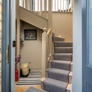 Inspiration for a small farmhouse carpeted curved wood railing staircase in Gloucestershire with wood risers.