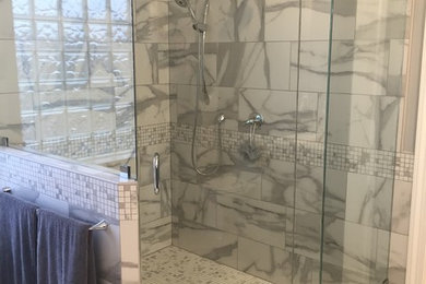 Inspiration for a mid-sized transitional gray tile, white tile and stone tile marble floor and white floor corner shower remodel in Other with gray walls and a hinged shower door