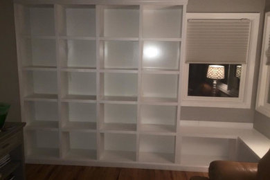 Large elegant open concept medium tone wood floor living room library photo in Denver with beige walls and a media wall